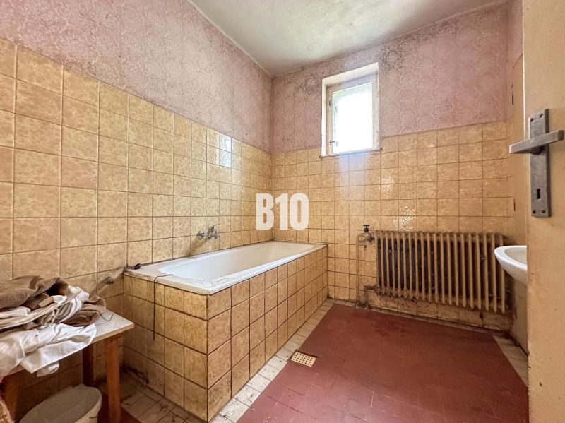 Ein Badezimmer in einem Einfamilienhaus mit einer Badewanne und keramischen Fliesen an den Wänden.