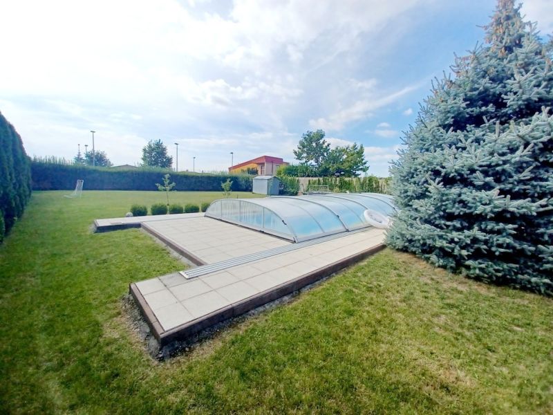 Ein Einfamilienhaus in Nové Zámky mit einem Pool im Garten und einer Kiefer.