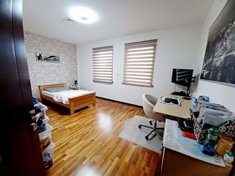 Ein Zimmer in einem Einfamilienhaus mit einem Bett, einem Schreibtisch und einem Boden mit Holzdekor.