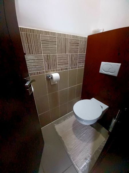 Badezimmer im Einfamilienhaus mit Keramikfliesen und hängender Toilette.