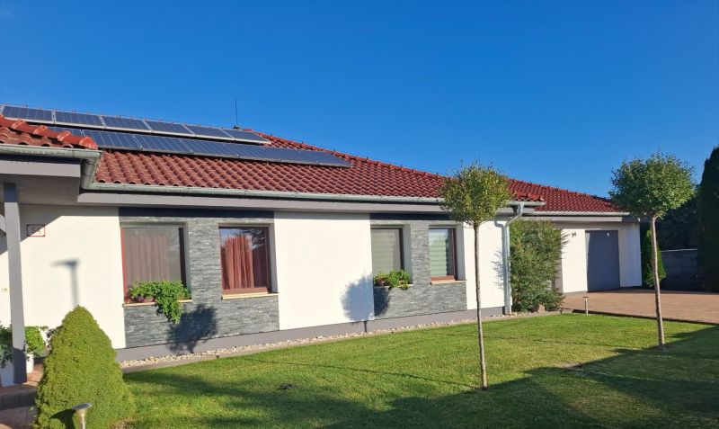 Ein Einfamilienhaus in Nové Zámky mit Solarpaneelen auf dem Dach und einem gepflegten Garten.