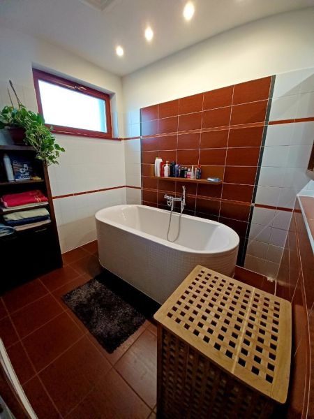 Badezimmer in einem Einfamilienhaus mit Badewanne, Regal und Wäschekorb.