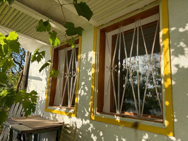 Ein Fenster mit gelbem Rahmen und Gitter, überflutet von Sonnenlicht in einer Hütte in Banka.
