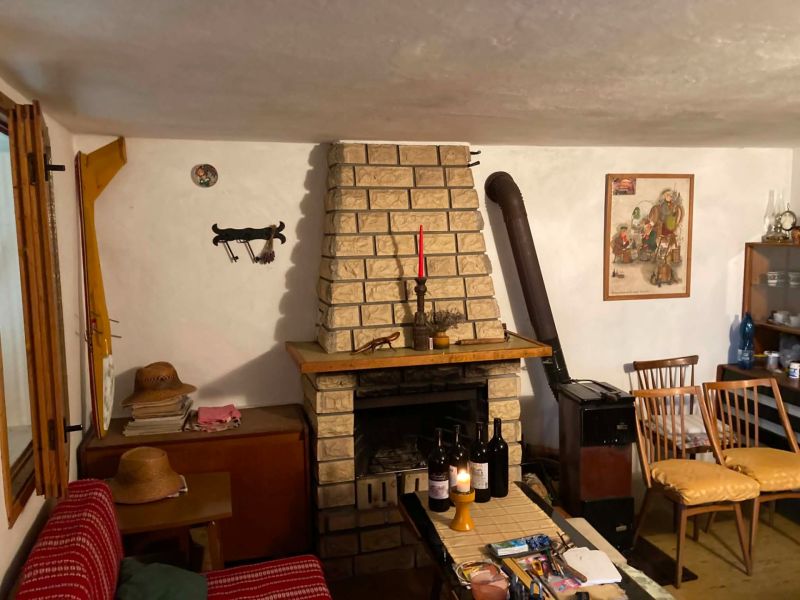 Ein Zimmer in einer Hütte mit Kamin, Holzstühlen und mehreren Weinflaschen auf dem Tisch.
