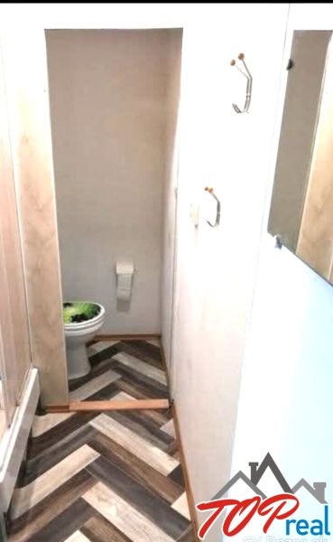 Badezimmer mit Toilette und Holzboden in einer Einzimmerwohnung.