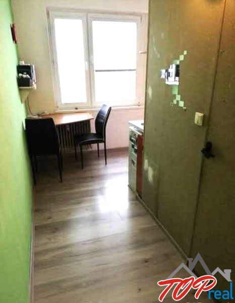 Küche in einer Einzimmerwohnung mit Holzboden-Dekor und einem Tisch am Fenster.