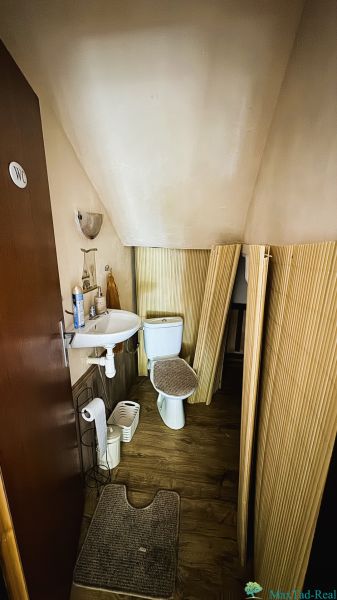 Badezimmer mit Toilette und Waschbecken, Boden mit Holzdekor, Einfamilienhaus.