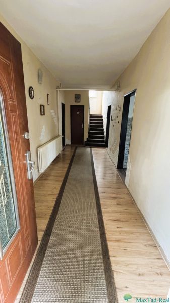 Eingangsflur in einem Einfamilienhaus mit einem Boden in Holzoptik und einem Teppichläufer.