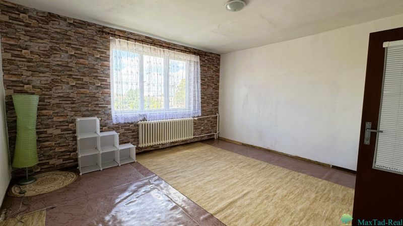 Ein Zimmer mit einem großen Fenster, einem Teppich und einer Ziegelmusterwand in einem Einfamilienhaus.