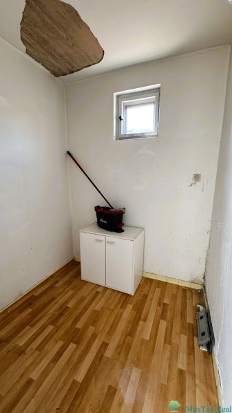 Ein kleiner Raum mit einem Fenster, einem Schrank und einem Boden mit Holzdekor in einem Einfamilienhaus.