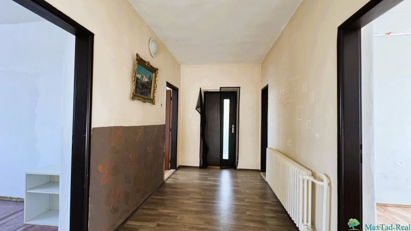 Ein Flur in einem Einfamilienhaus mit einem Holzboden und einem Bild an der Wand.