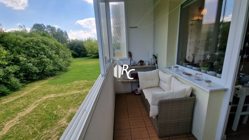 Eine verglaste Loggia mit Blick ins Grüne, eine gemütliche Couch und Dekorationen, 1-Zimmer-Wohnung.