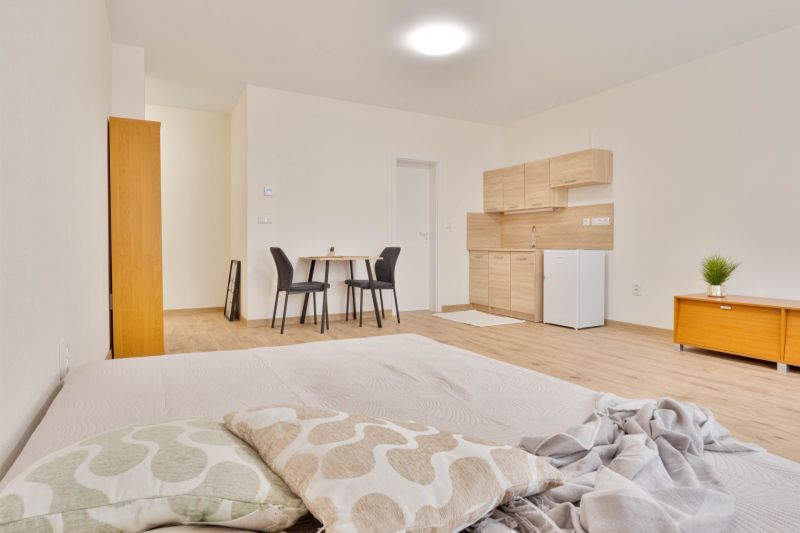Einzimmerwohnung mit Holzboden, Küchenzeile, Esstisch für zwei Personen.