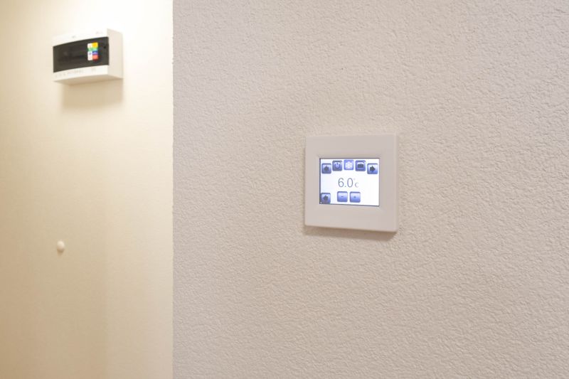 Ein einstellbares Thermostat an der Wand in einem Studio-Apartment, schlichtes Design, weißer Hintergrund.