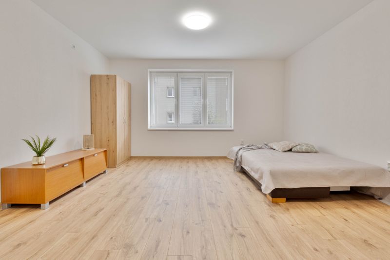 Ein Studio-Apartment mit Holzboden, Bett und Schrank, neutrale Farben.