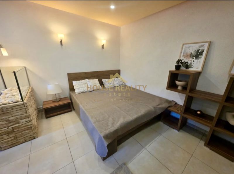 Schlafzimmer in einer Einzimmerwohnung mit stilvollem Dekor, Holzelementen, geräumigem Bett.