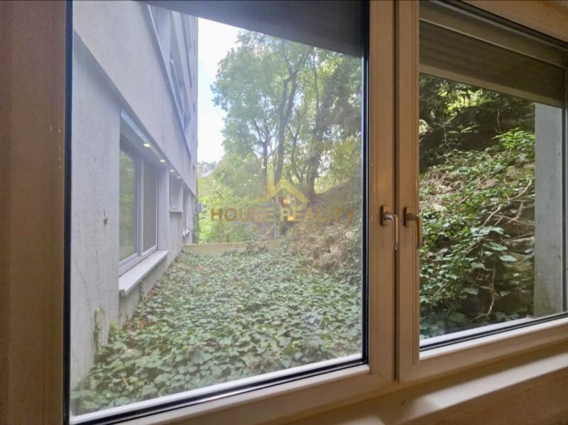 Der Blick aus dem Fenster einer Einzimmerwohnung auf das Grün und das Nachbargebäude.
