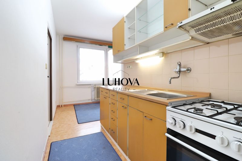 Küche in einer 2-Zimmer-Wohnung mit Küchenzeile, Herd und großem Fenster.