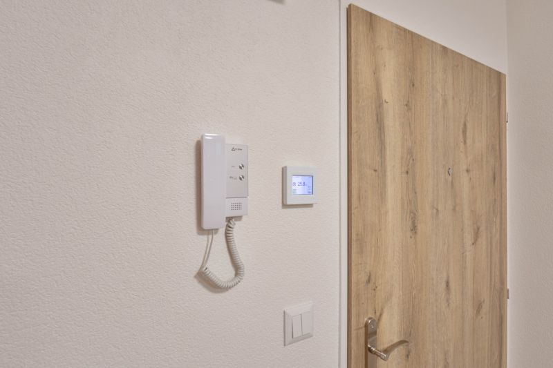 Türen mit Holzdekor und Gegensprechanlage in einem Einzimmerapartment.
