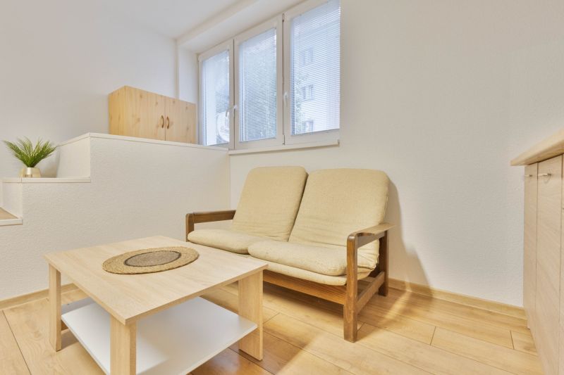 Einzimmerwohnung mit Sofa, Tisch und Holzboden.