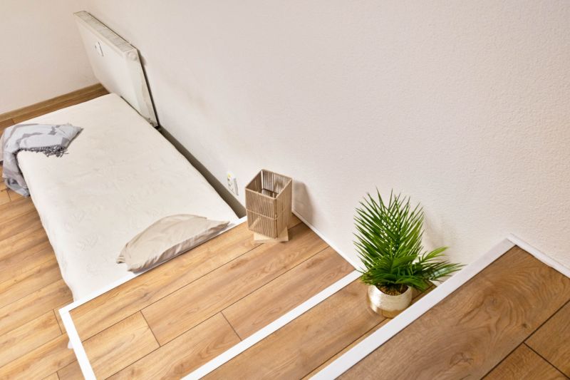 Ein Studio mit Holzboden, einem Bett und einer Topfpflanze.