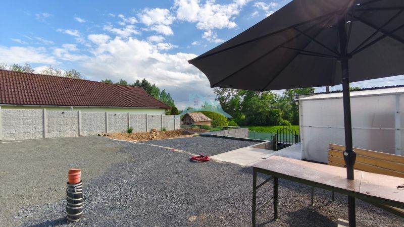 Ein Hof mit steinernem Belag und einem großen Sonnenschirm auf den Erholungsgrundstücken in Záhorce, Selešťany.