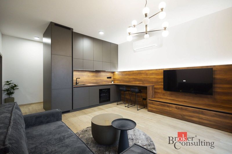 Küche in einer 2-Zimmer-Wohnung mit Holzboden und Wandfernseher.