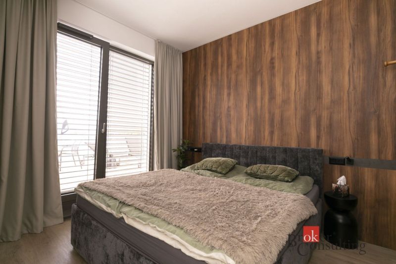 Doppelbett mit weicher Decke in einer 2-Zimmer-Wohnung mit Holzboden.