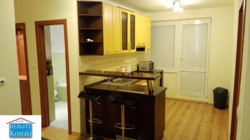 Küchenecke mit gelben Schränken und Theke in einer 3-Zimmer-Wohnung, Boden mit Holzdekor.