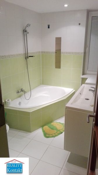 Badezimmer mit Eckbadewanne und grünen Fliesen in einer 3-Zimmer-Wohnung.