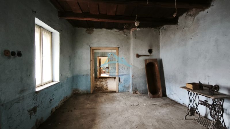 Ein Zimmer in einem Einfamilienhaus mit blauen Wänden, einer alten Nähmaschine und einem hölzernen Trog.