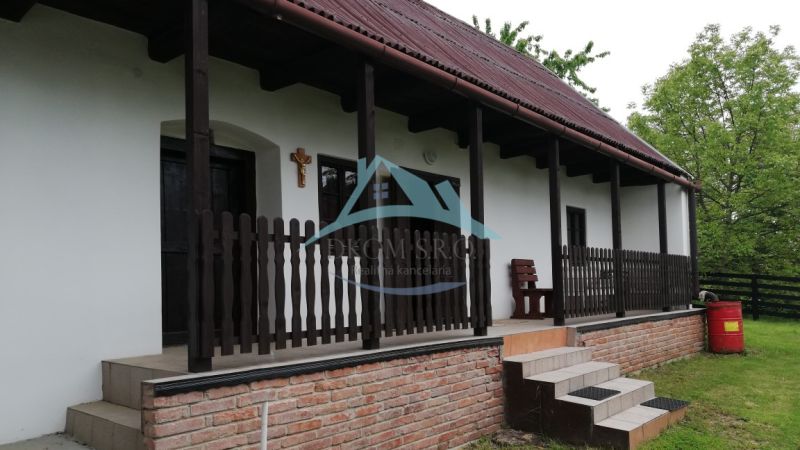 Ein Einfamilienhaus mit Terrasse, Holzzaun und Ziegelgrundlage in einer natürlichen Umgebung.
