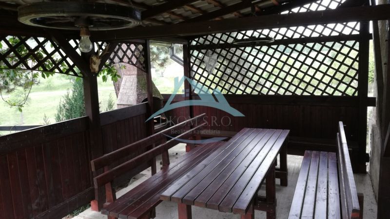 Ein hölzerner Pavillon mit Bänken im Garten eines Einfamilienhauses.
