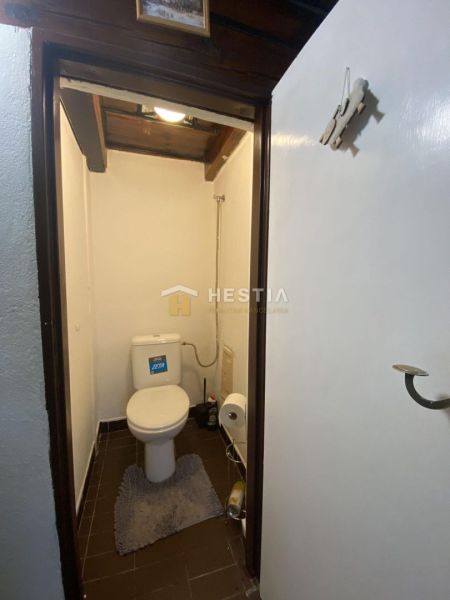 Toilette im Einfamilienhaus mit dunklen Fliesen und weißen Wänden.