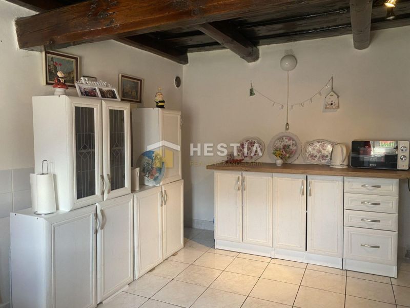 Küche in einem Einfamilienhaus mit Holzbalken und weißen Schränken.