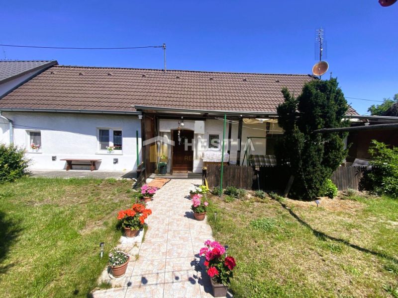 Ein Einfamilienhaus in Borský Mikuláš mit Garten und Blumen in Töpfen vor der Veranda.