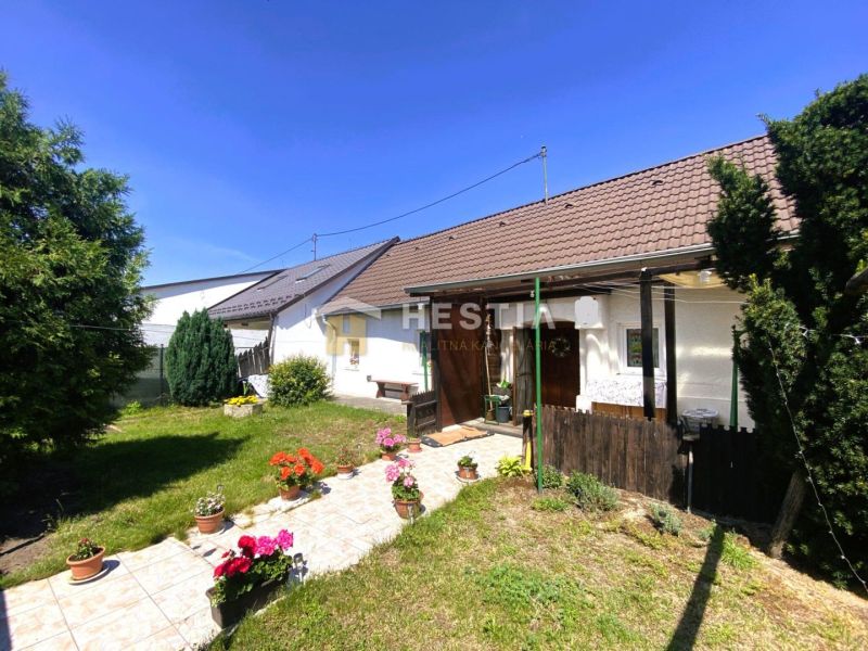 Ein Einfamilienhaus in Borský Mikuláš mit Garten, Blumen und Rasen im sonnigen Hof.