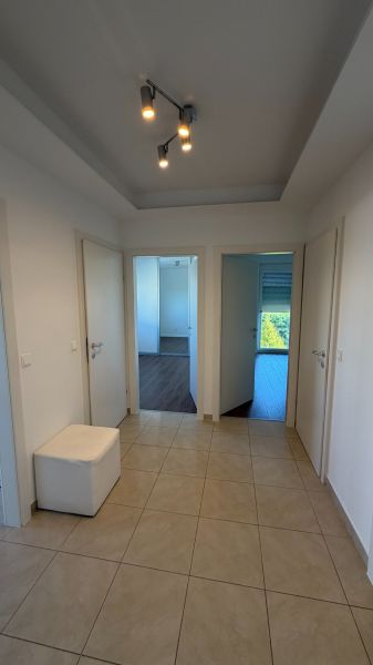 Der Flur in der 3-Zimmer-Wohnung mit Keramikfliesen und drei weißen Türen.
