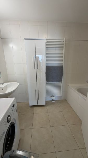Badezimmer in einer 3-Zimmer-Wohnung, mit weißen Möbeln und Waschmaschine.