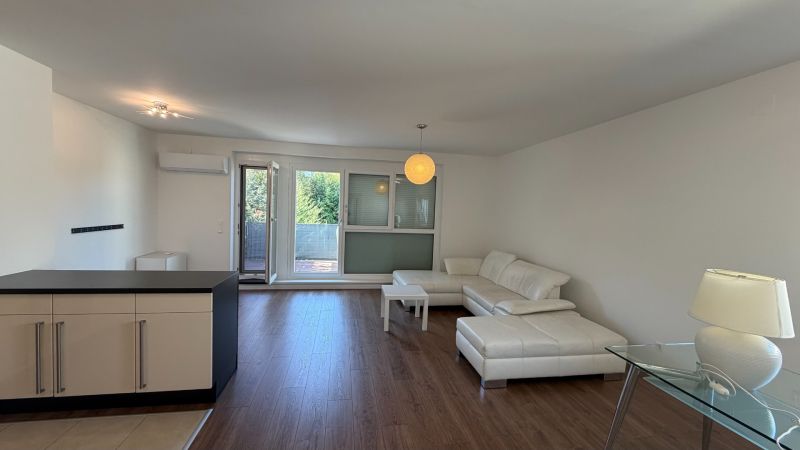 Wohnzimmer in einer 3-Zimmer-Wohnung mit weißem Sofa und Boden in Holzoptik.
