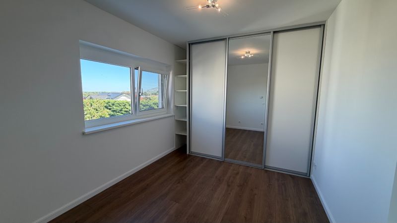Ein Zimmer in einer 3-Zimmer-Wohnung mit einem Boden in Holzoptik und einem Einbauschrank.