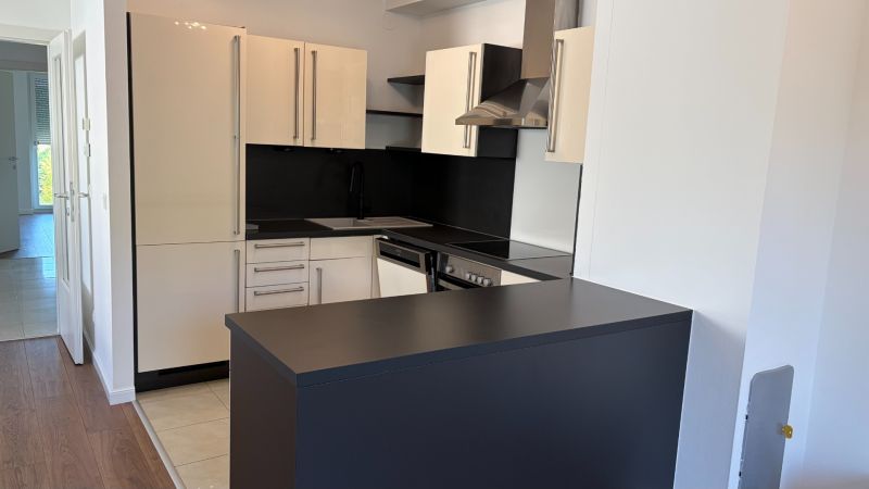 Küche in einer 3-Zimmer-Wohnung mit eleganter schwarzer Arbeitsplatte und hellen Schränken.