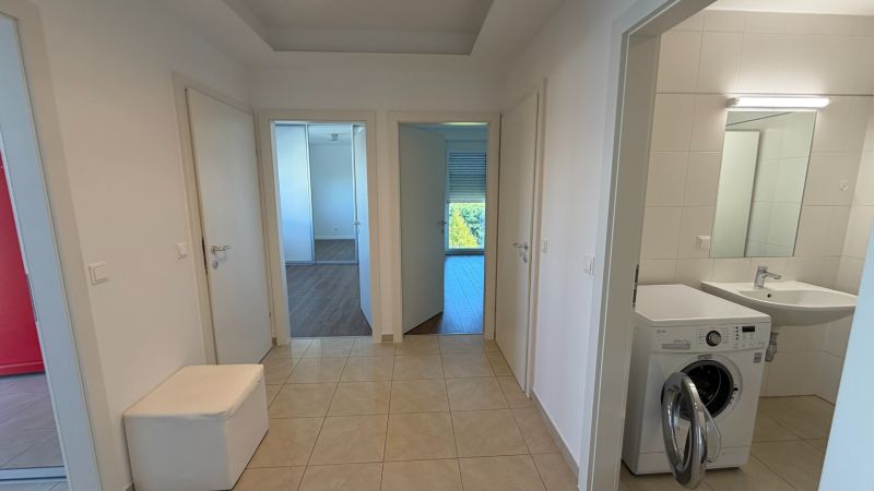 In einem 3-Zimmer-Wohnung mit Holzboden und einer Waschmaschine im Badezimmer.