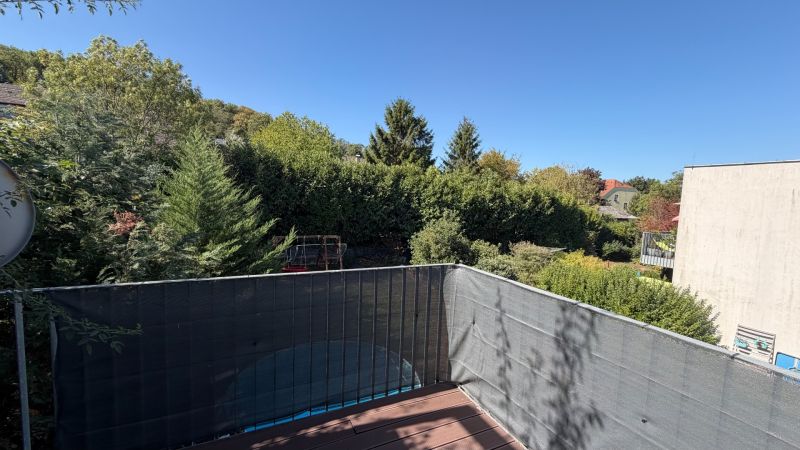 Terrasse einer 3-Zimmer-Wohnung in Wolfsthal mit Blick auf Grünflächen und blauen Himmel.