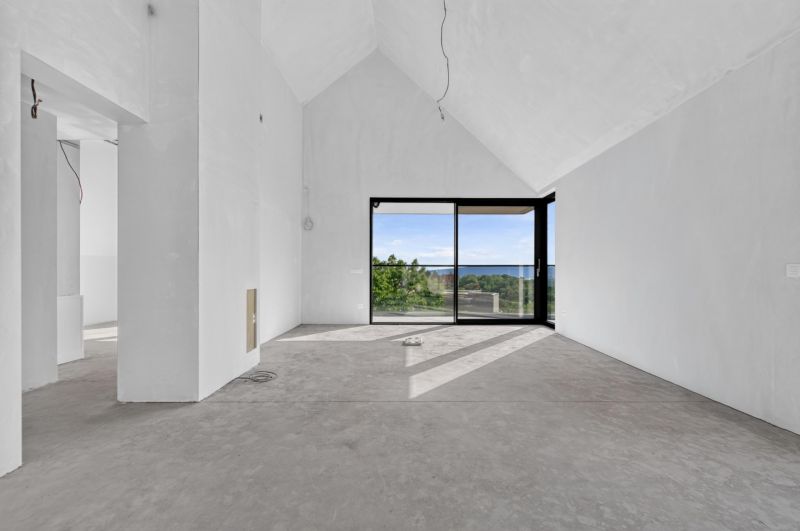 Ein geräumiges Wohnzimmer mit großen Fenstern in einer Wohnung mit 5 oder mehr Zimmern und Blick ins Grüne.