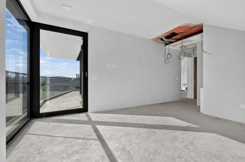 Ein Innenraum mit unfertigem Boden und Glastüren in einer Wohnung mit 5 oder mehr Zimmern.