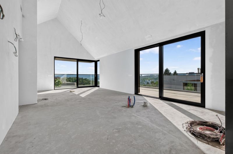 Ein geräumiges Zimmer in einer Wohnung mit 5 oder mehr Zimmern mit großen Fenstern und Betonboden.