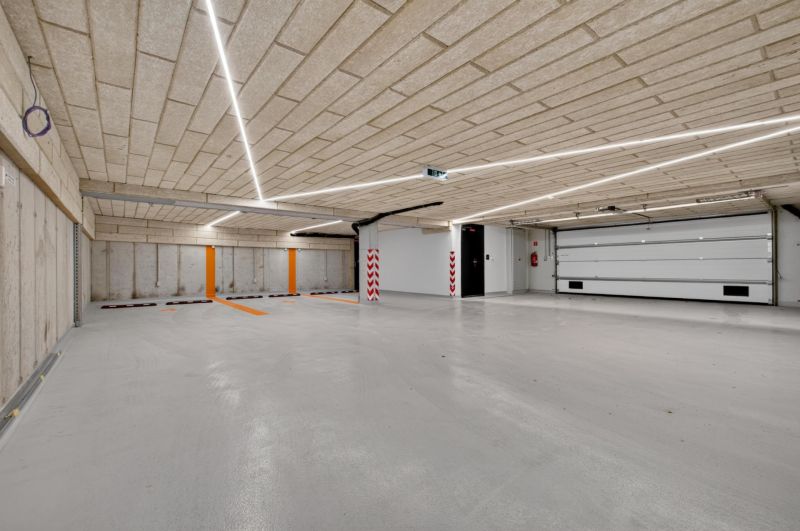Parkhaus mit Betondecke und -boden, beleuchtet mit linearen Leuchten.