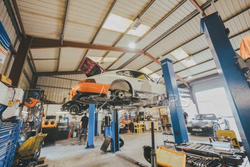 Auto-Service mit zwei Hebebühnen, Fahrzeugen und Werkzeugen in einem speziellen Immobilienbereich.