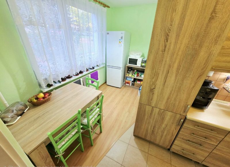 Küche in einer 4-Zimmer-Wohnung mit Tisch, grünen Stühlen und Boden in Holzoptik.